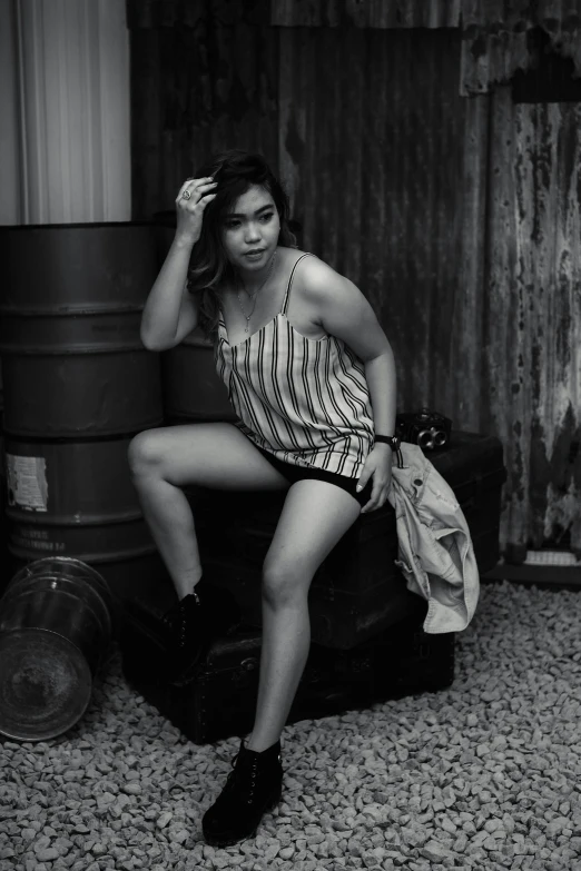 black and white pograph of a woman sitting on a suitcase