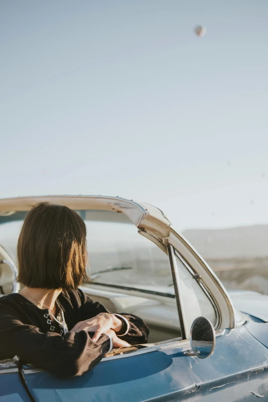 a young woman is looking at her cell phone in a vintage car