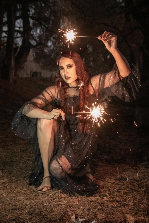 girl sitting on the ground holding up sparklers