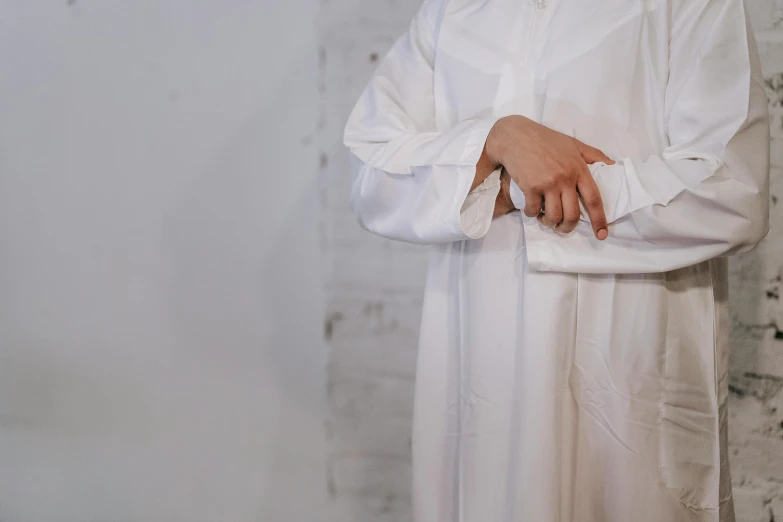 a man in a white suit stands against a wall