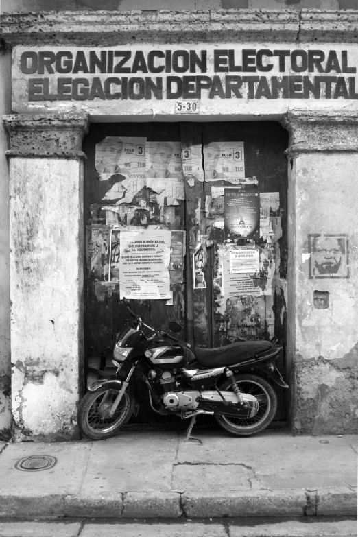 black and white pograph of a motorcycle sitting in front of a door