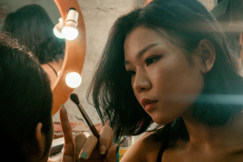 a woman is putting on makeup while looking into the mirror