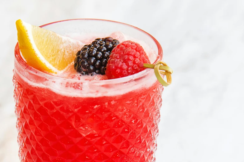 raspberry lemonade and blackberry dainty cocktail in a red glass