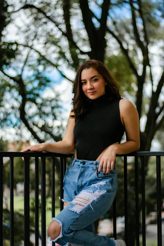 a beautiful young lady standing in front of a black fence