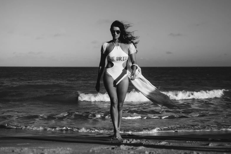 a woman in a bathing suit carries a surfboard along the ocean