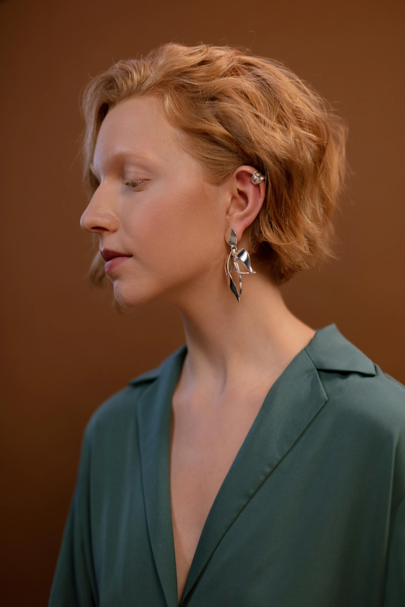 woman with blonde hair wearing a green blouse and earrings