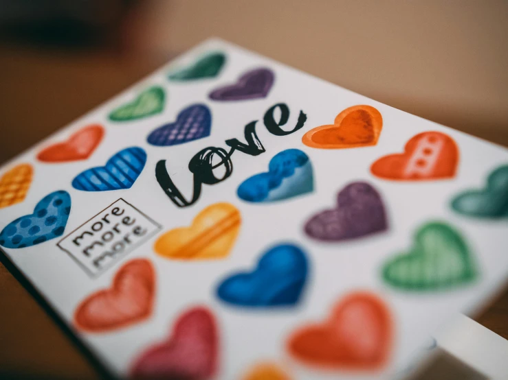 a white card with multi - colored hearts and the word love