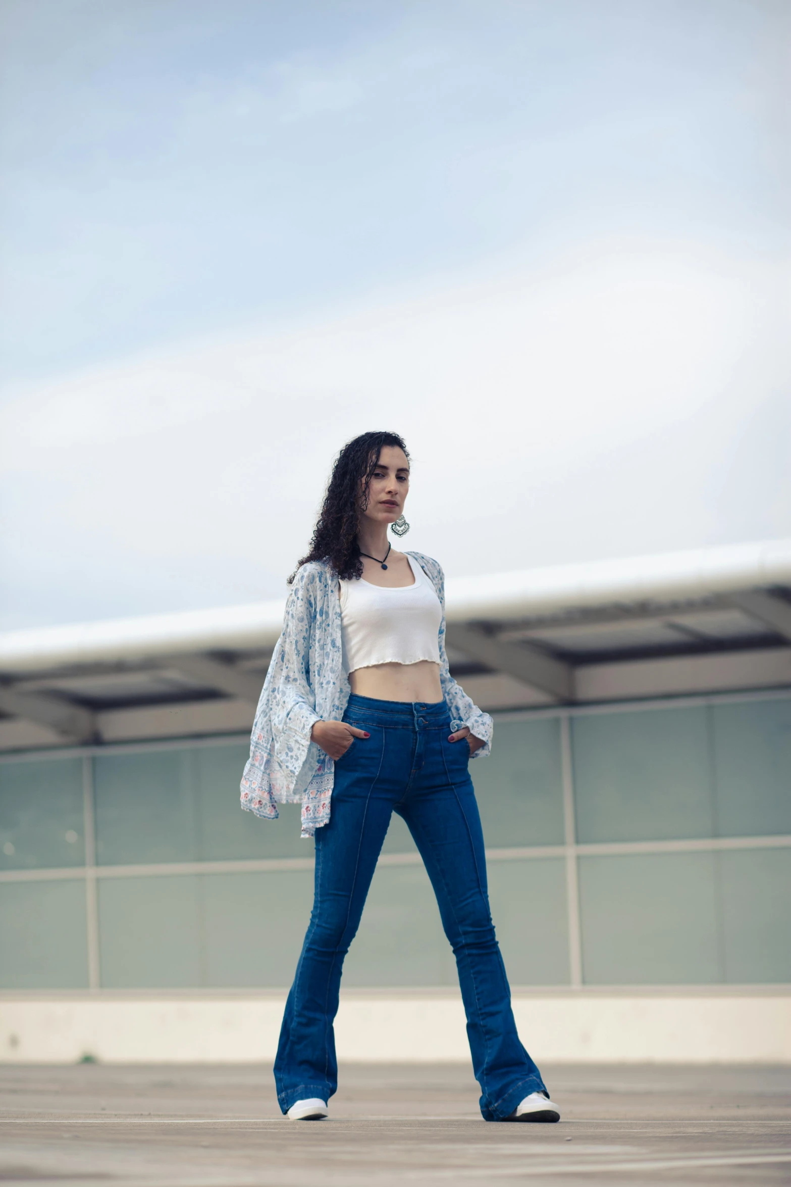 a woman in a white top and blue jeans walking down an airport