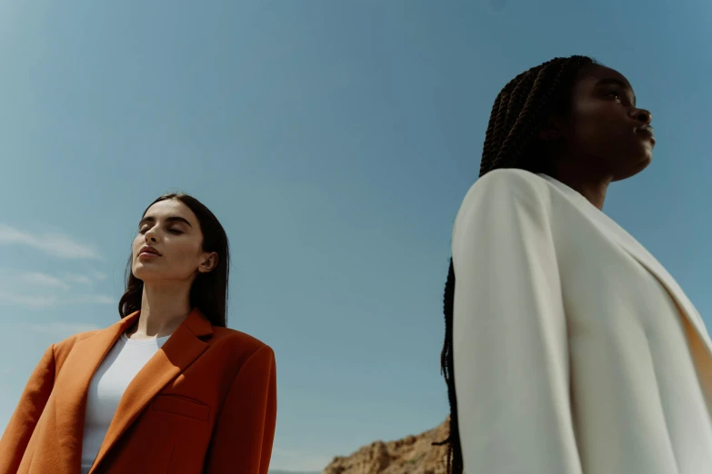 two women in orange and white jackets facing away