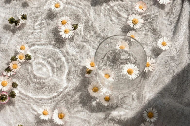 daisy buds falling into an empty vase on white fabric