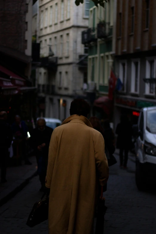a man wearing a coat is walking down a street