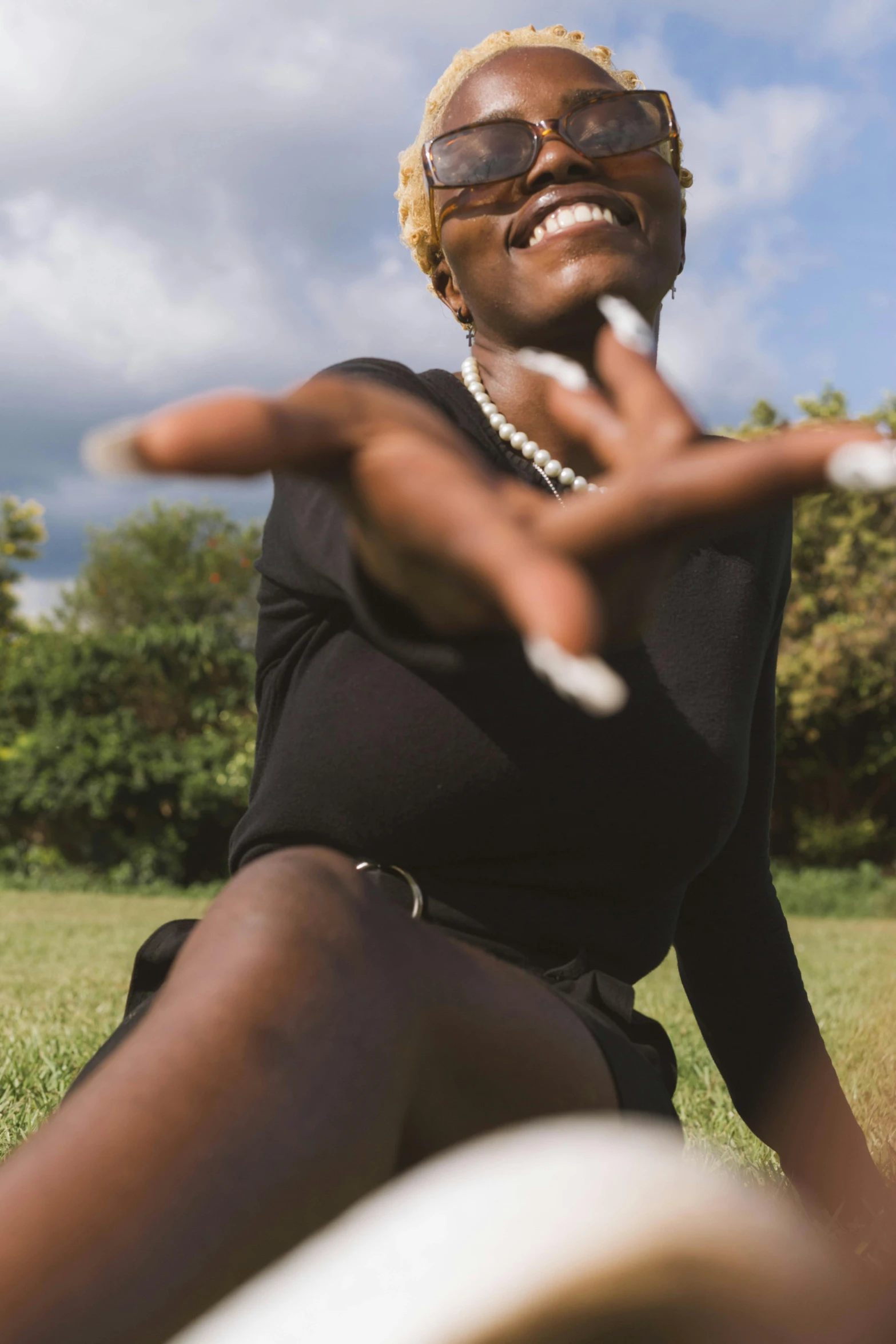 a woman is sitting on the grass and throwing some stones