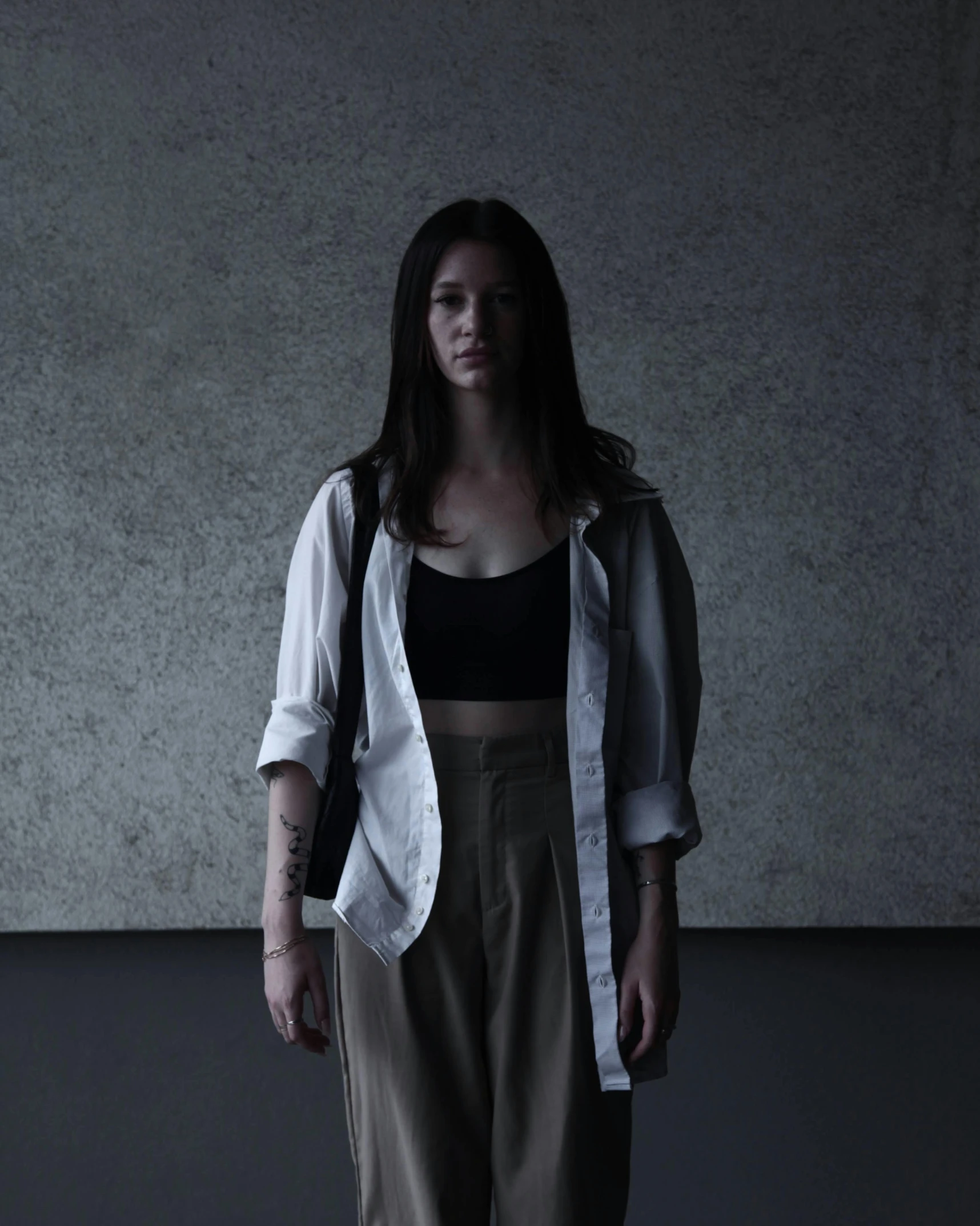 a woman standing against a wall while wearing a white jacket