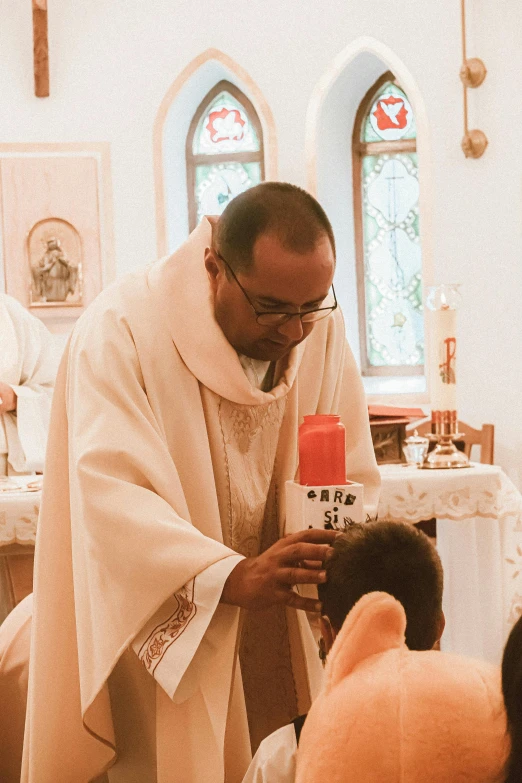 a man in white robes putting a bottle of soing in a child's hand