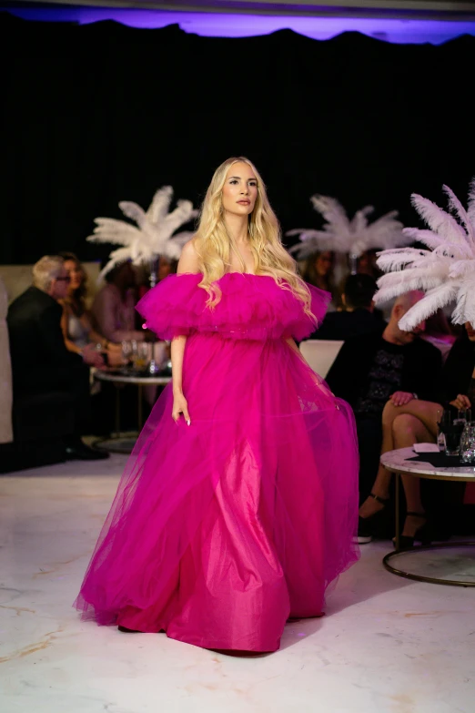 a lady in a pink dress walks the runway
