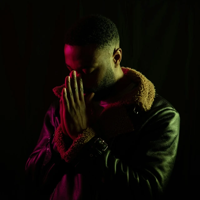 a man in a jacket praying and making a gesture