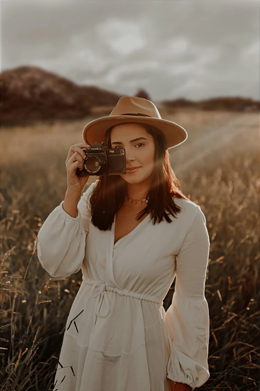 a woman is standing in a field while holding a camera