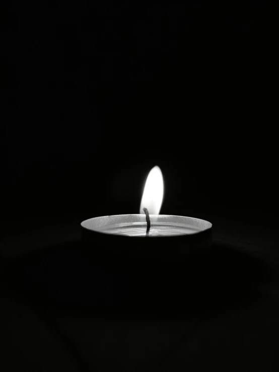 a lit candle is on a plate in the dark