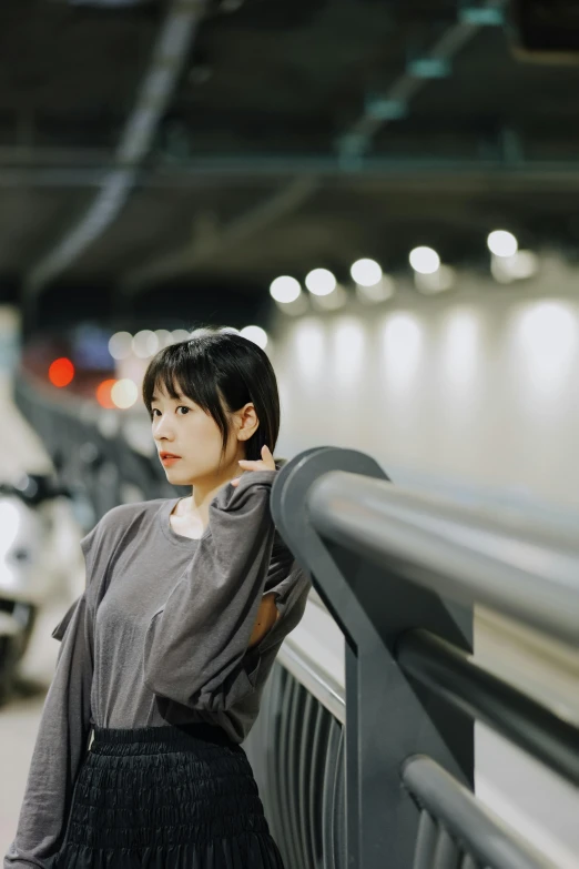 young woman in grey top leaning on railing near car