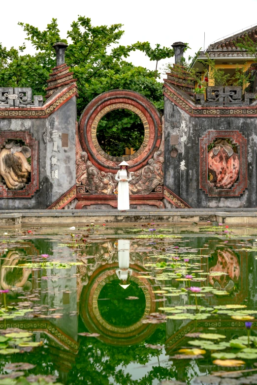 a pond with algaes in it with a brick wall and decorative decorations on top