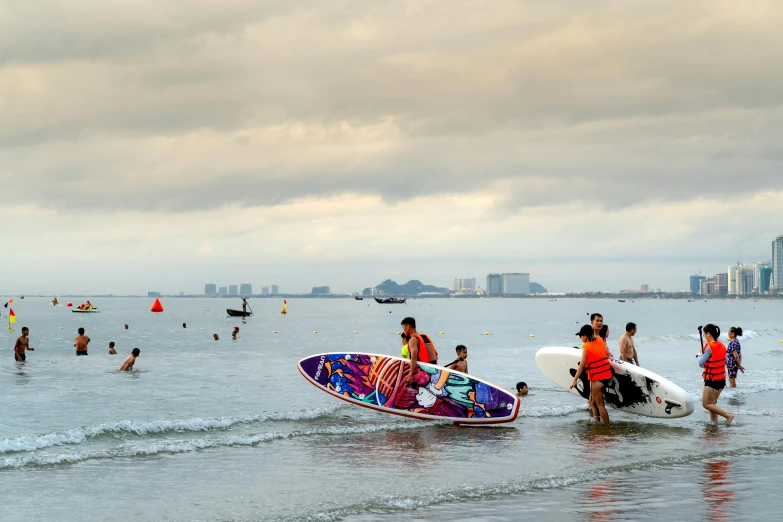 people are walking through the surf in front of some surfboards