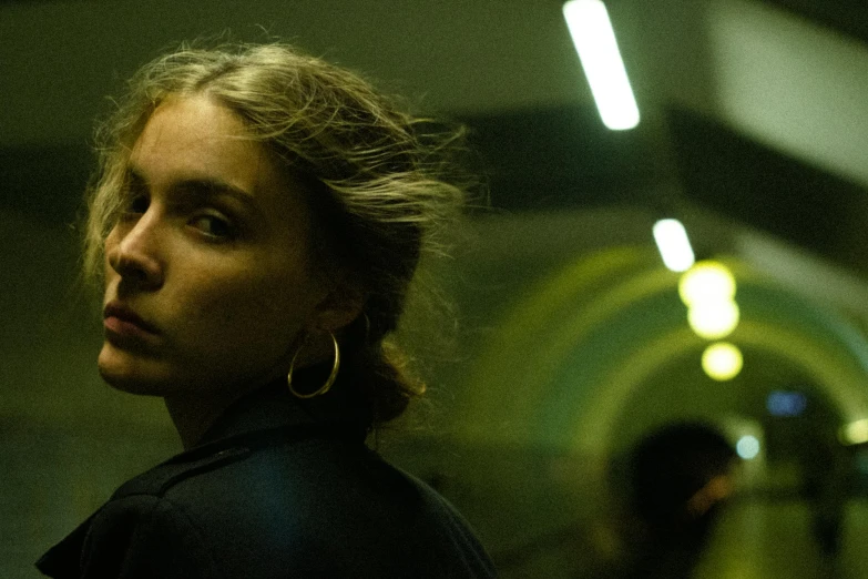 a woman wearing large earrings in an empty room