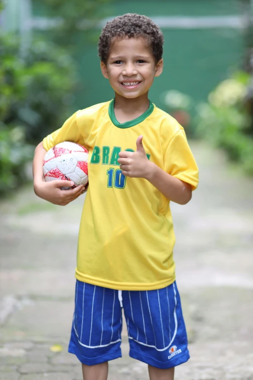 the boy smiles while holding his soccer ball