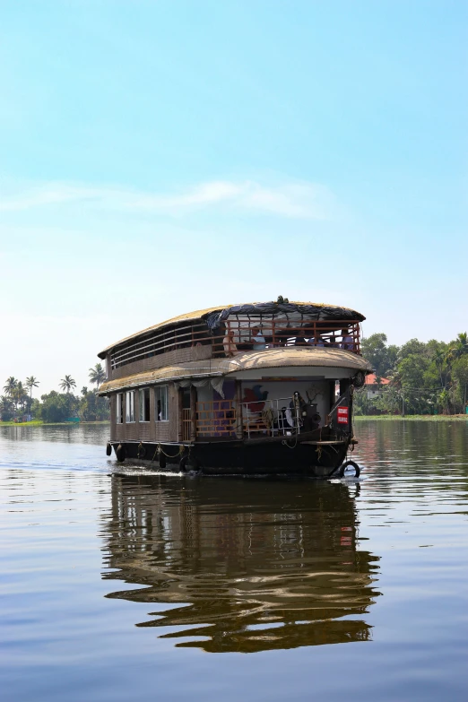 people and luggage on top of a house boat floating down a river