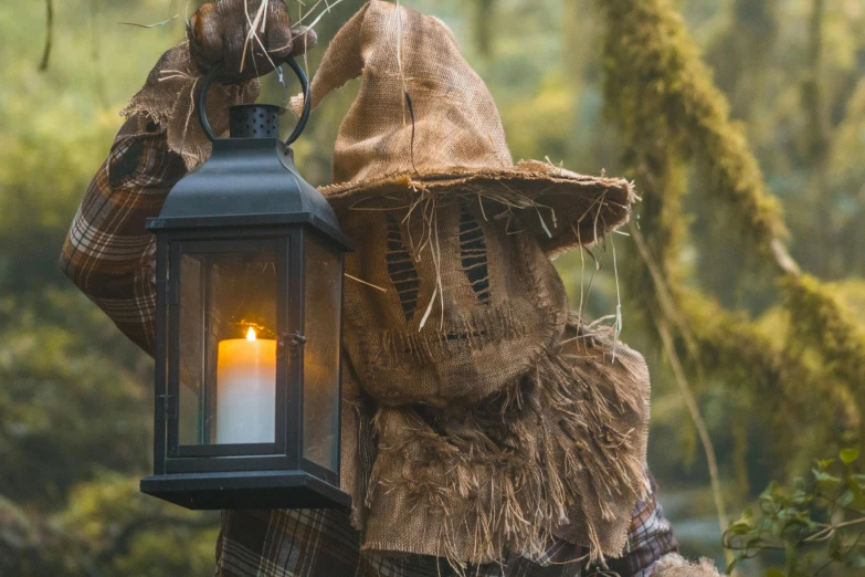 a lit candle placed inside a lantern in a forest