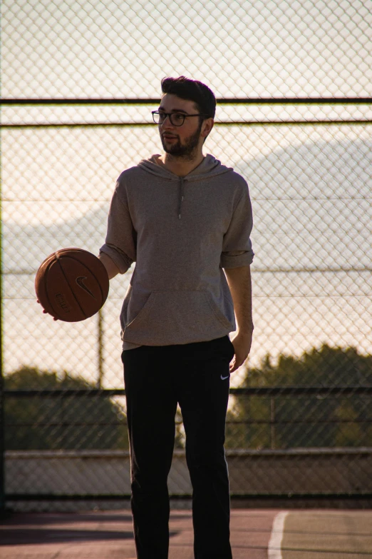 man holding a basketball wearing a hoodie