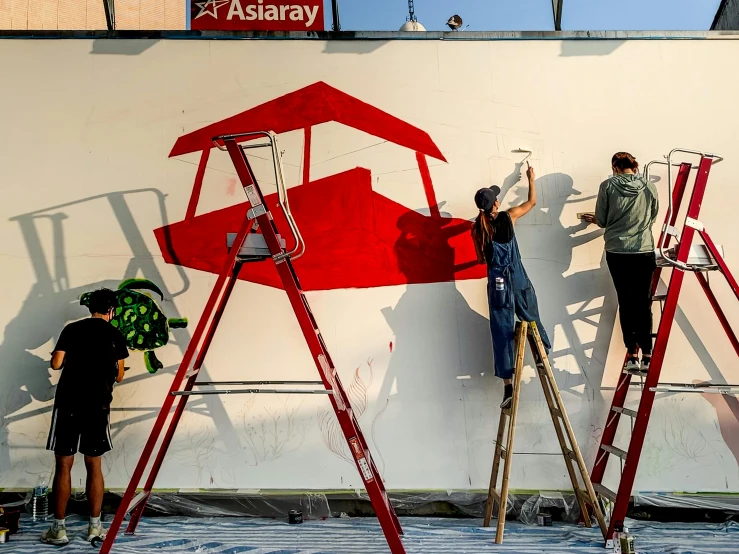 people painting a big white ship with red accents