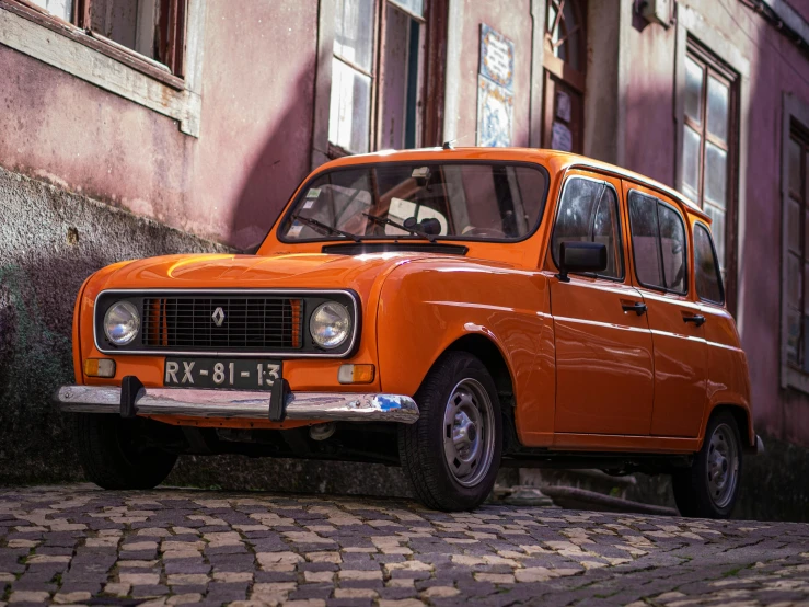 an orange car is parked next to a brick building