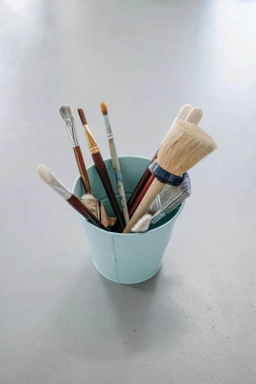 a cup is holding many brushes and other household tools