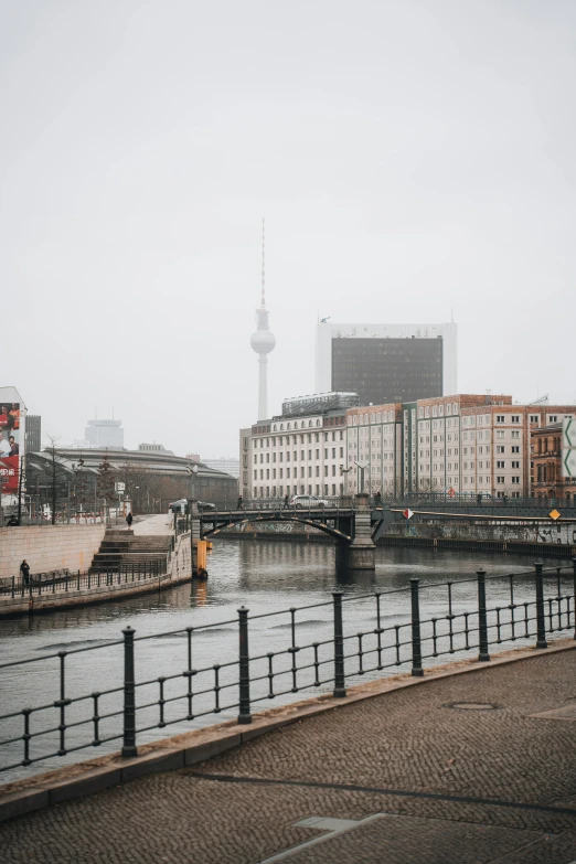 a body of water with buildings and bridge in the background