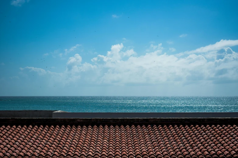 blue ocean with clouds, waves and a red roof