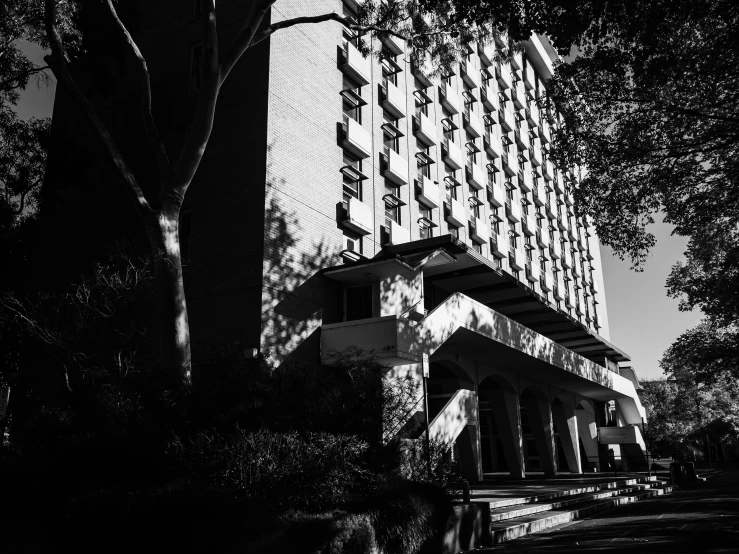 a black and white image of a building with trees in the background