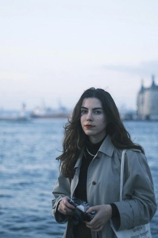 a woman in black is holding a camera by the water