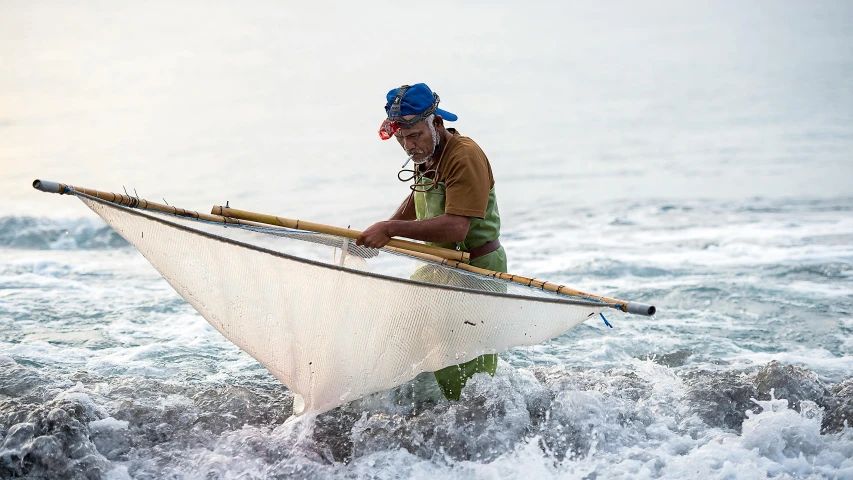 a man carrying a boat into the waves