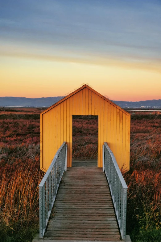 a wooden walkway leading into a yellow building