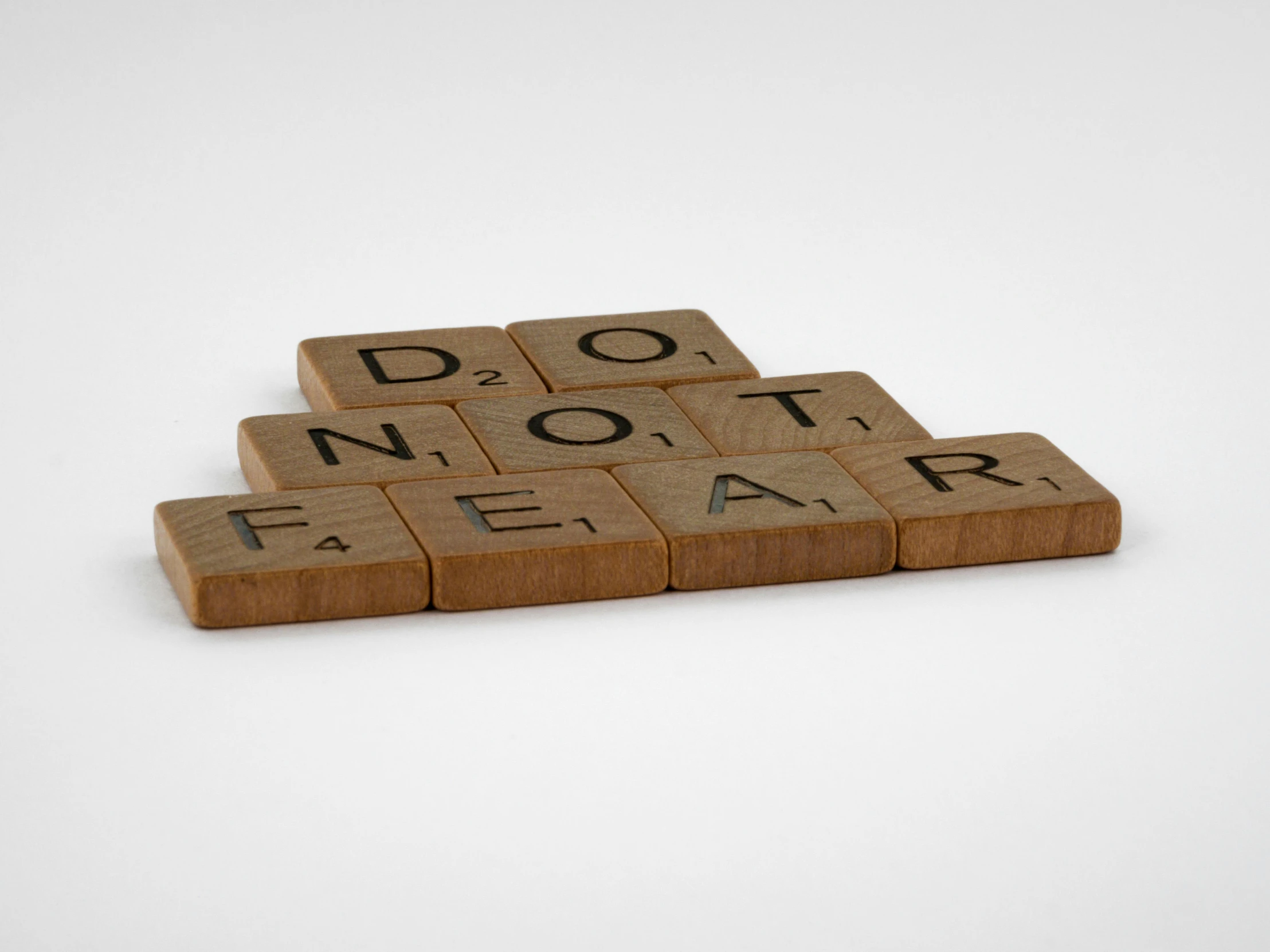 four wooden blocks spelling do not fear on a white background