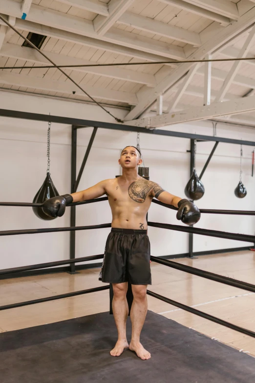 a man in shorts and boxing gloves stands in a gym