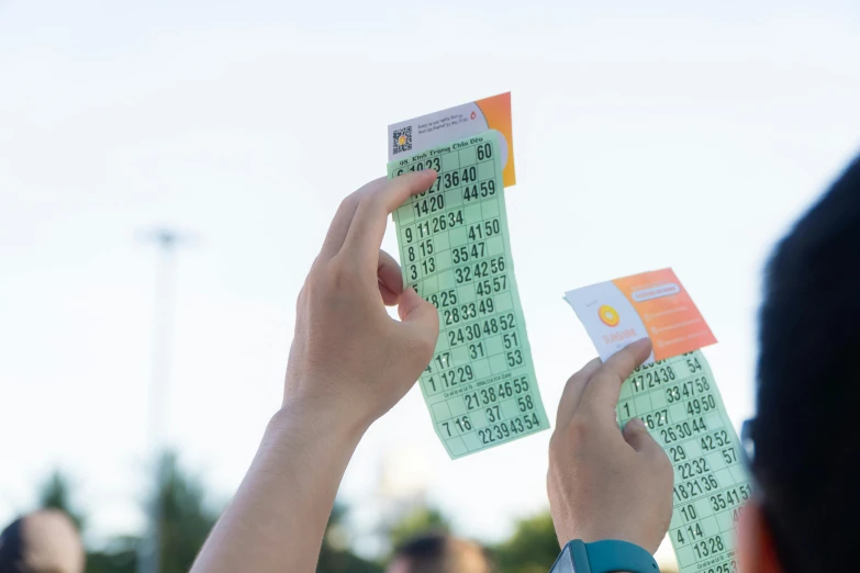 a person holds up two tickets in front of a crowd