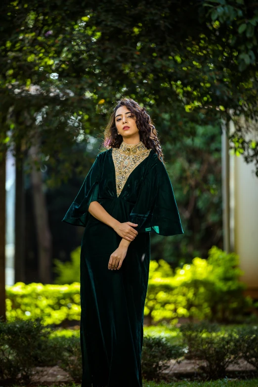 a woman in a green long dress standing outside