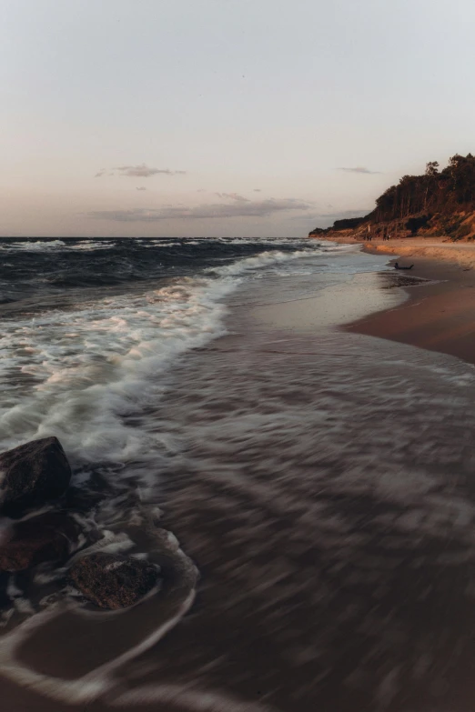 a sandy beach with a wave coming in towards the shore