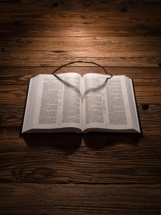 a lighted bible laying on a wooden table