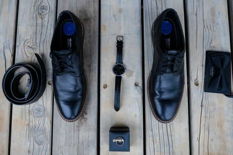 an assortment of men's clothing and shoes laid out on a wood deck