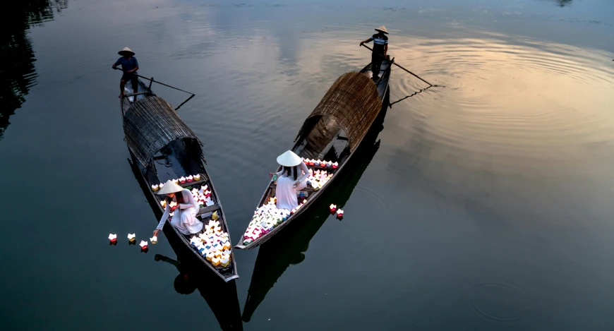 two boats in the water with candles floating on them