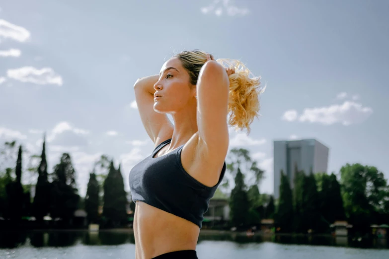 a woman in a top is by the water with her arms up