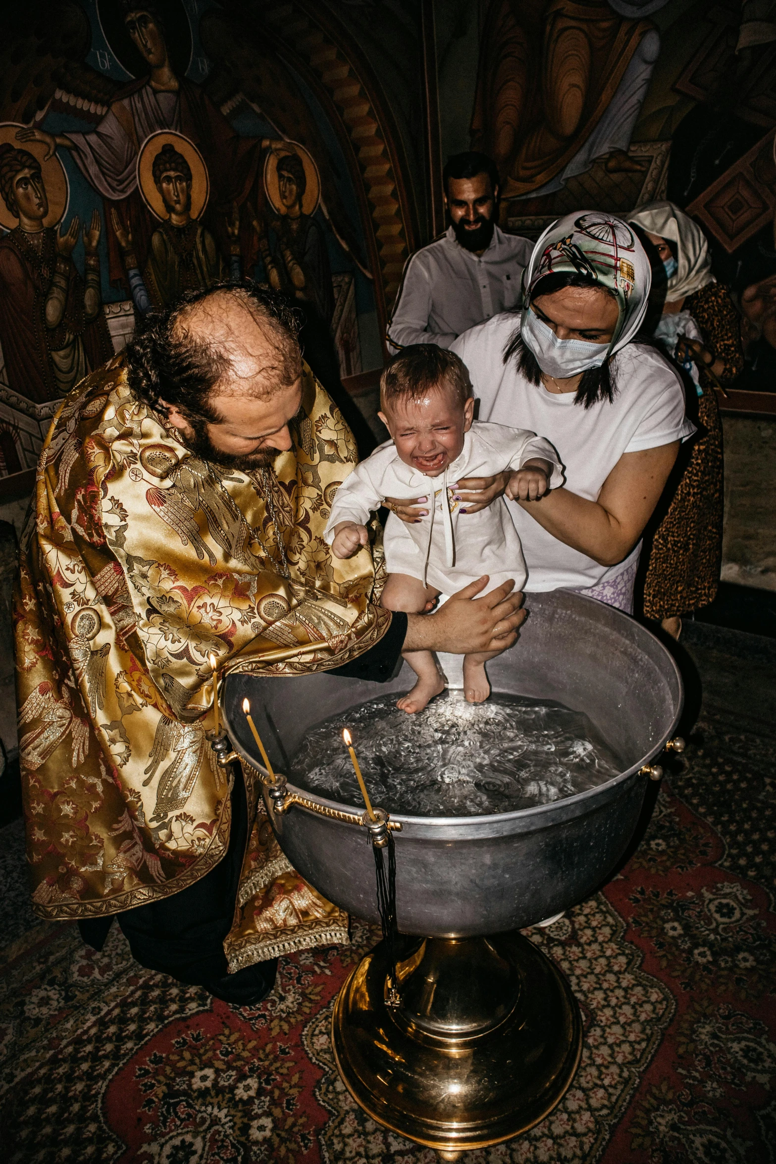 a group of people in a fancyly decorated setting hold a baby