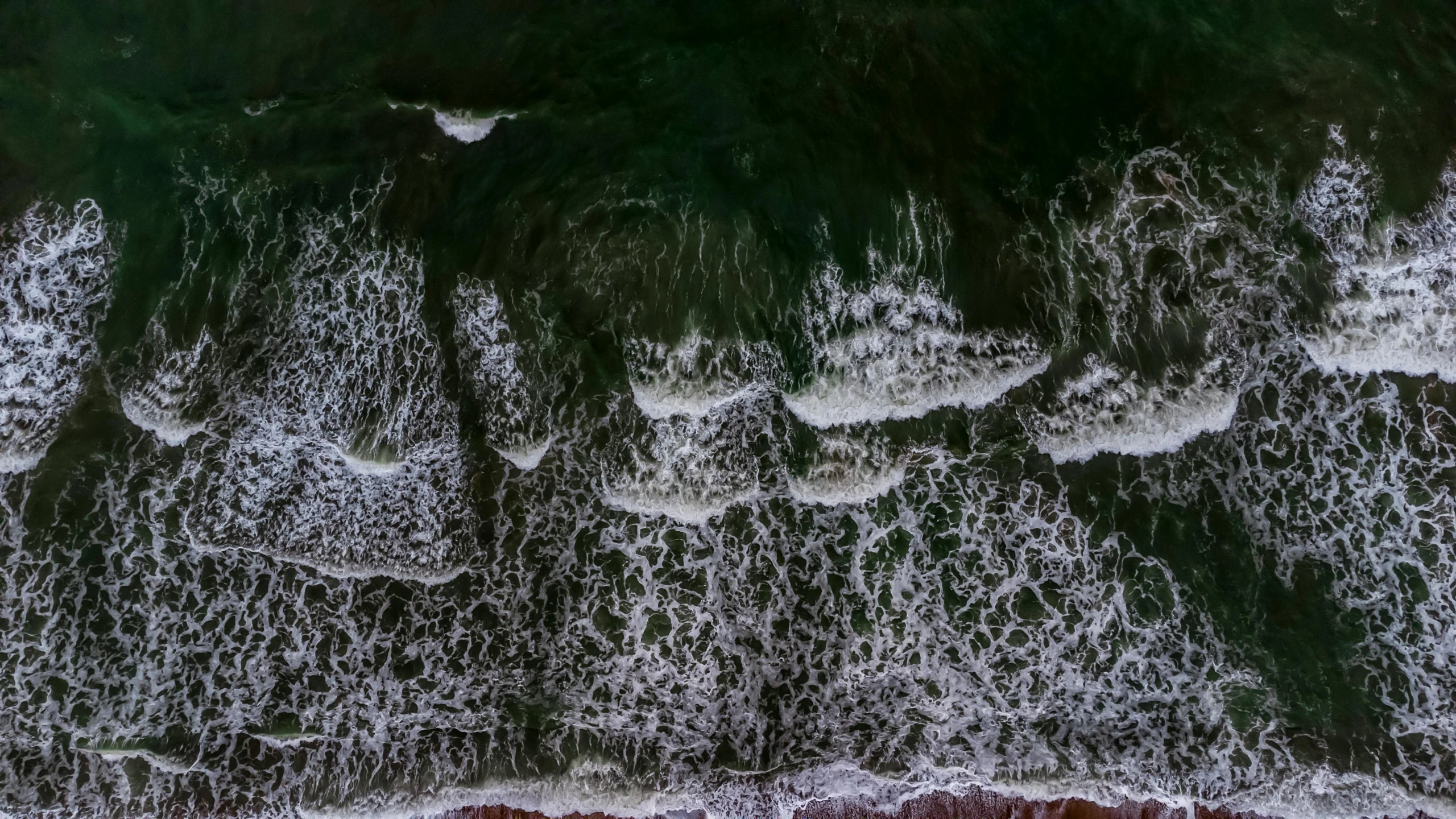 an aerial po of water rushing over a beach